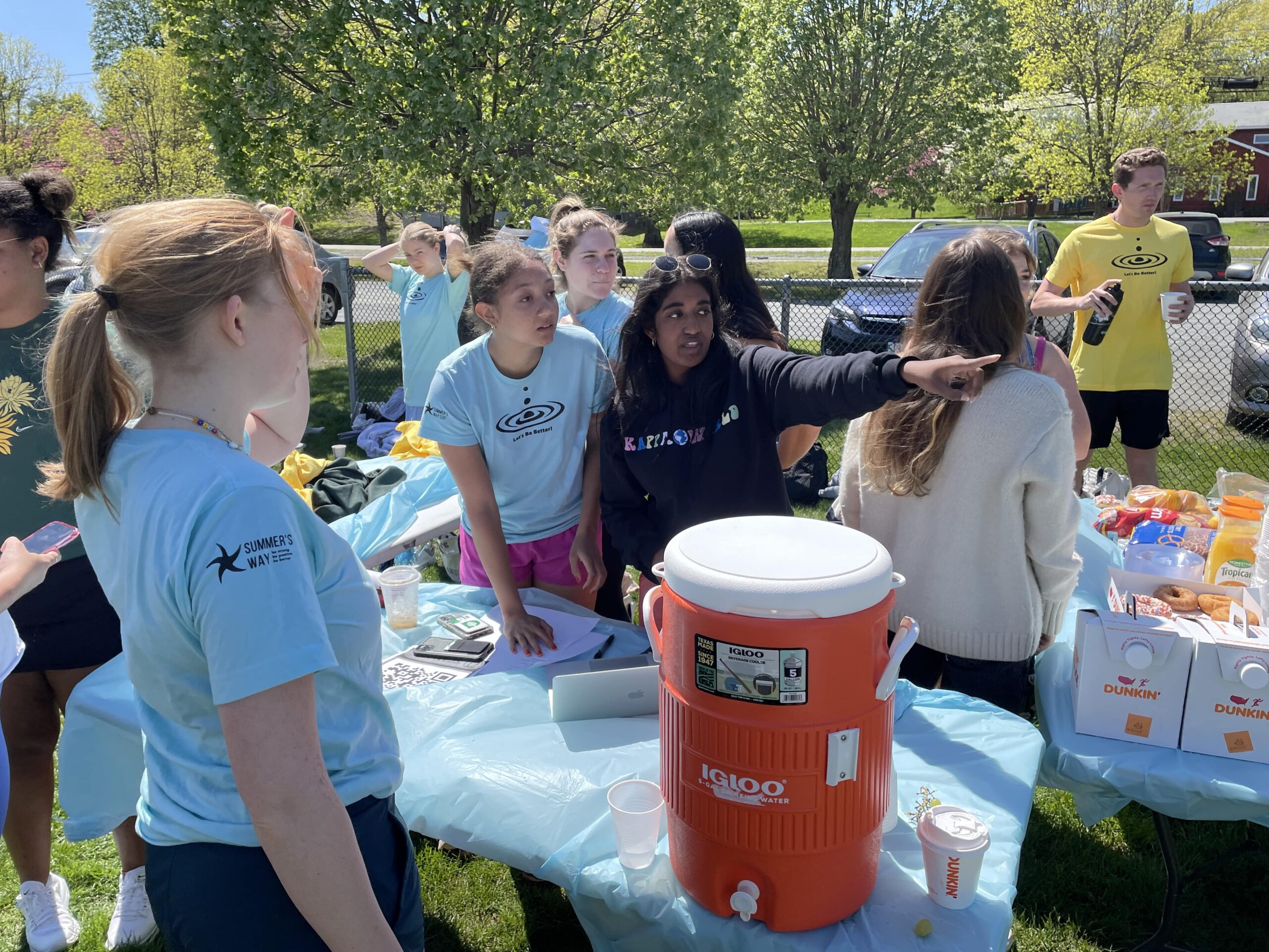 girls at an outside event next to a table with a large water container